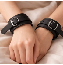 Czarne skórzane kajdanki na nadgarstkach dłoni